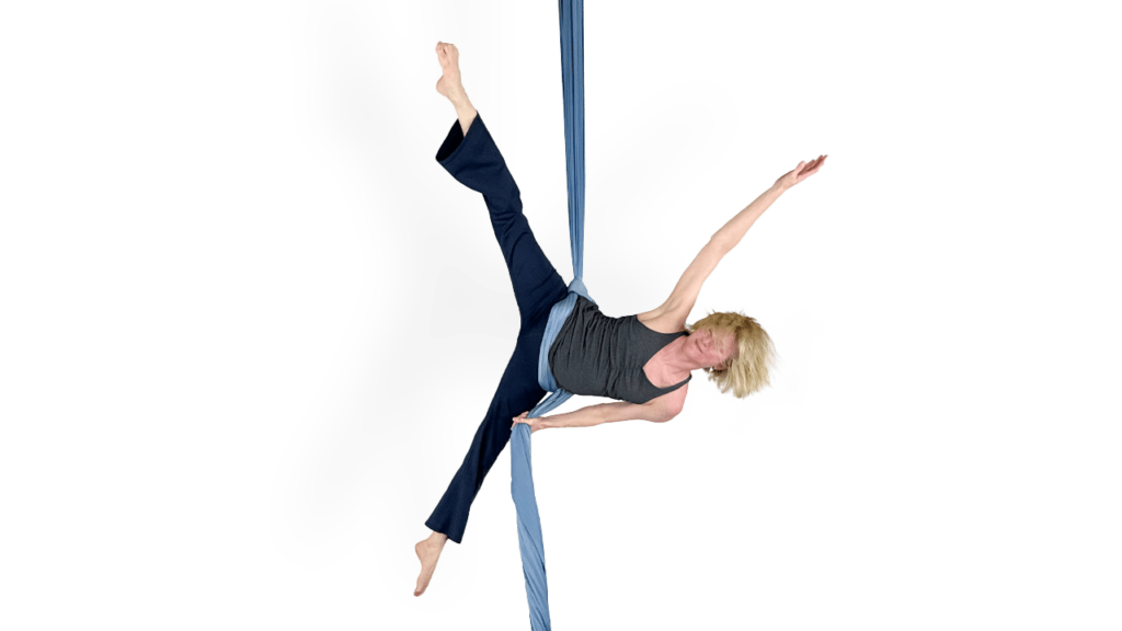 Person performing a Star Hollow Body Drill on blue aerial silks.